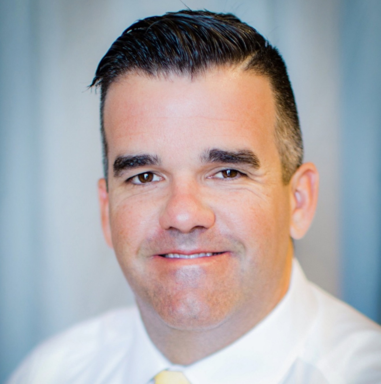 headshot of administrator smiling in front of white and blue background